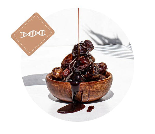 Thick syrup drizzled over a wooden bowl of dates from Just Date on a bright white surface.